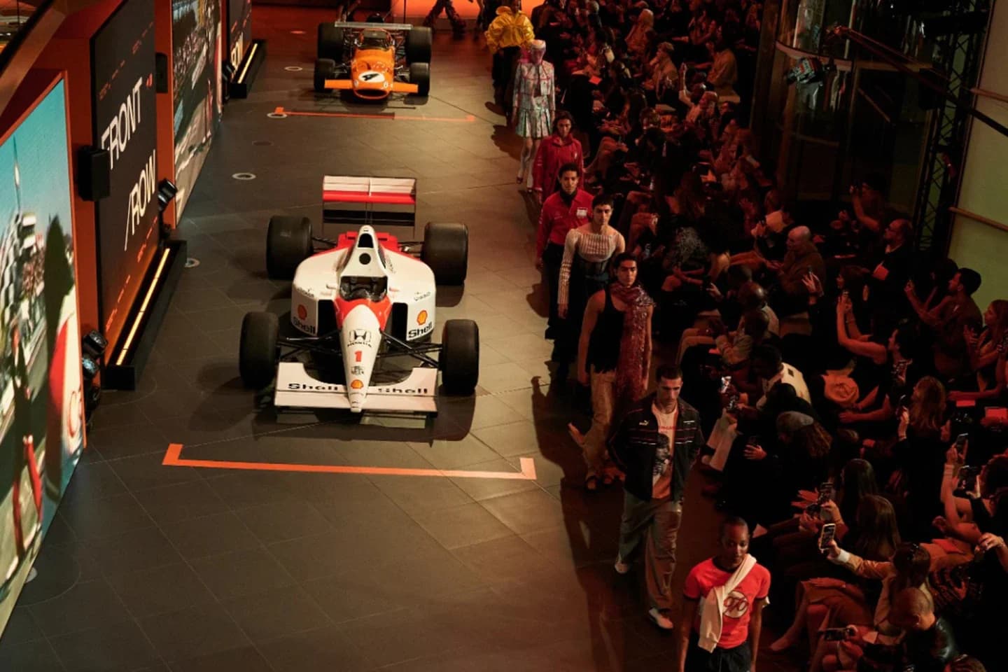 A McLaren Formula 1 car and models present the PUMA x James Hunt collection at an indoor runway event.