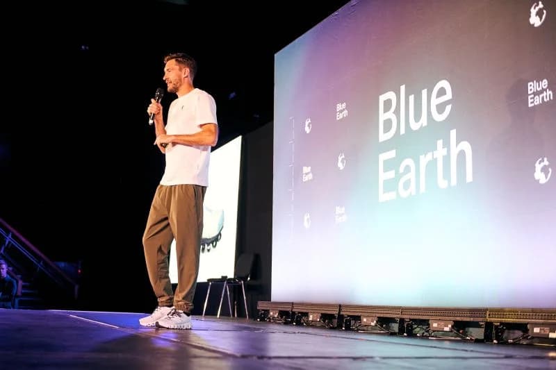 A speaker on stage beside Blue Earth Summit signage in a photo shared by On